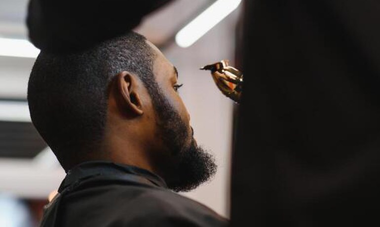 Barber lining up a client's beard and fade