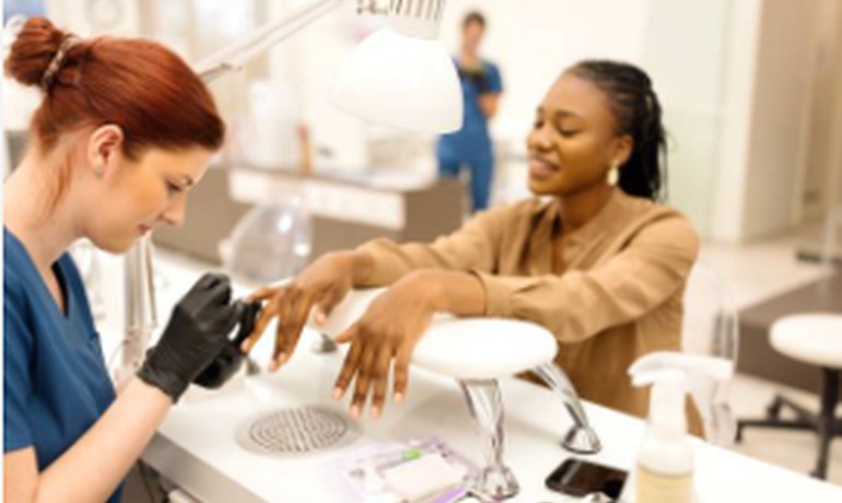 Nail technician working with a client at the nail station